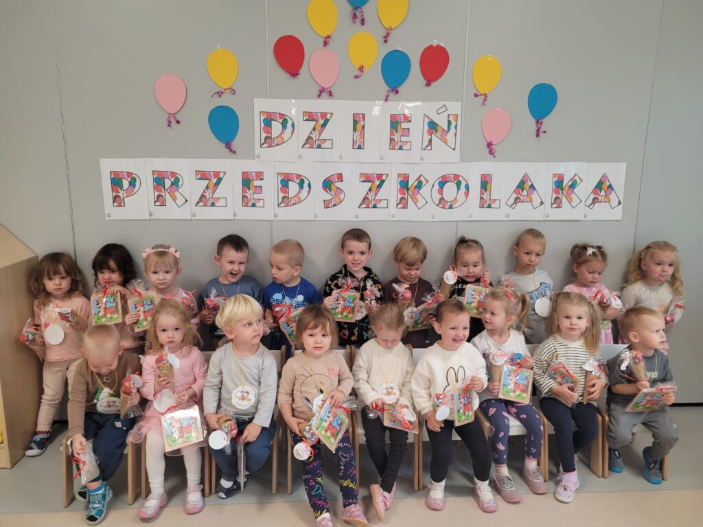 Cała grupa dzieci pozuje do zdjęcia na tle napisu Dzień Przedszkolaka