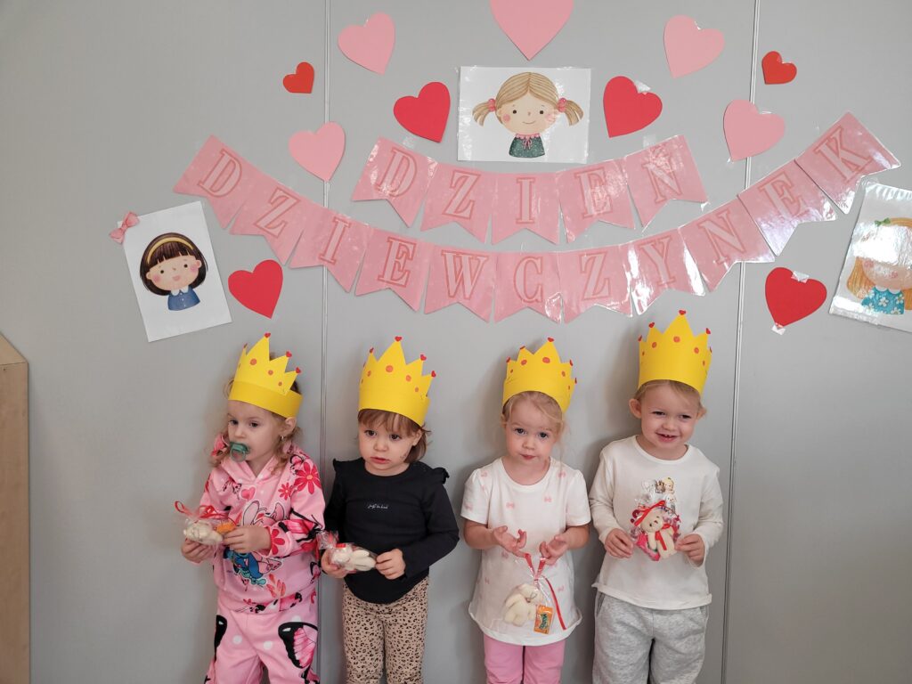 Cztery dziewczynki stoją na tle dekoracji z okazji Dnia Dziewczynki