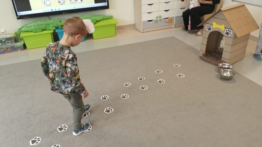 Chłopiec idzie po śladach psich łap w kierunku budy
