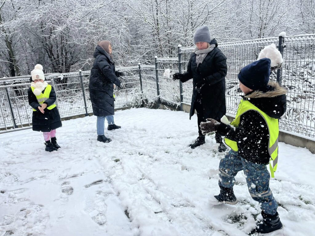 DZIECI Z NAUCZYCIELAMI RZUCAJĄ SIĘ ŚNIEŻKAMI