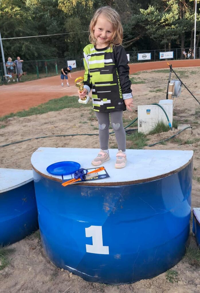 dziewczynka z pucharem w ręku stoi na podium z numerem 1