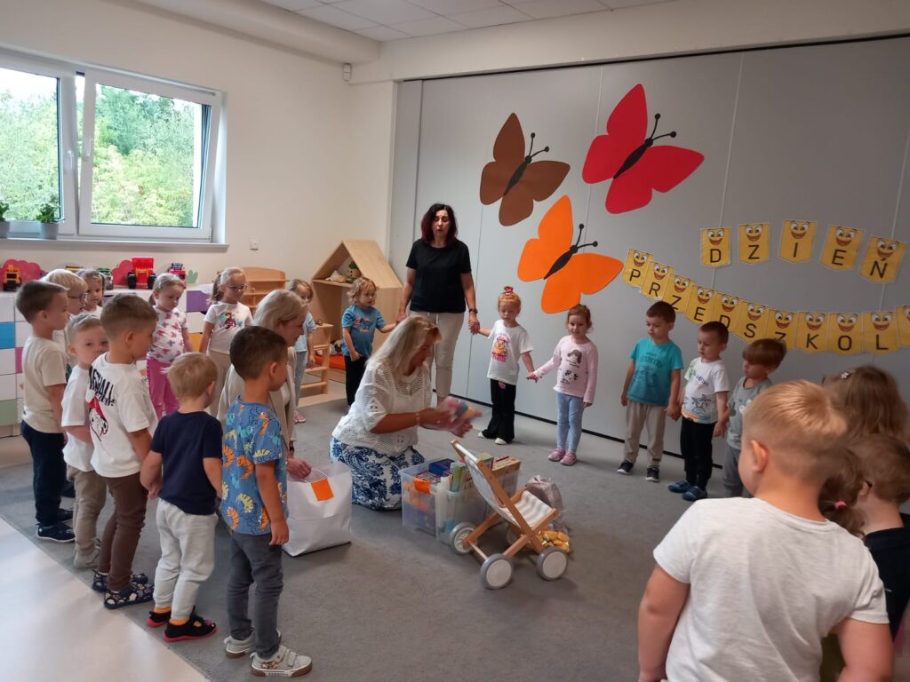 dzieci stoją w kole, otrzymują prezenty od pań