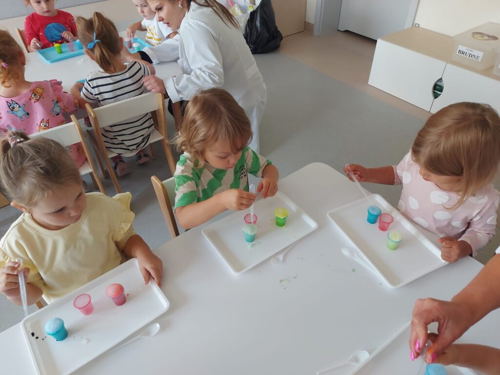 czworo dzieci siedzi przy stoliku i wykonuje eksperyment