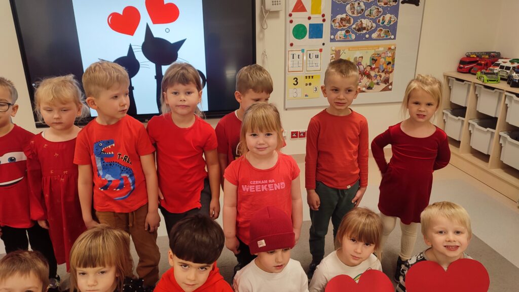 Grupa dzieci ubranych na czerwono pozuje do zdjęcia w rękach trzymają czerwone serca.
