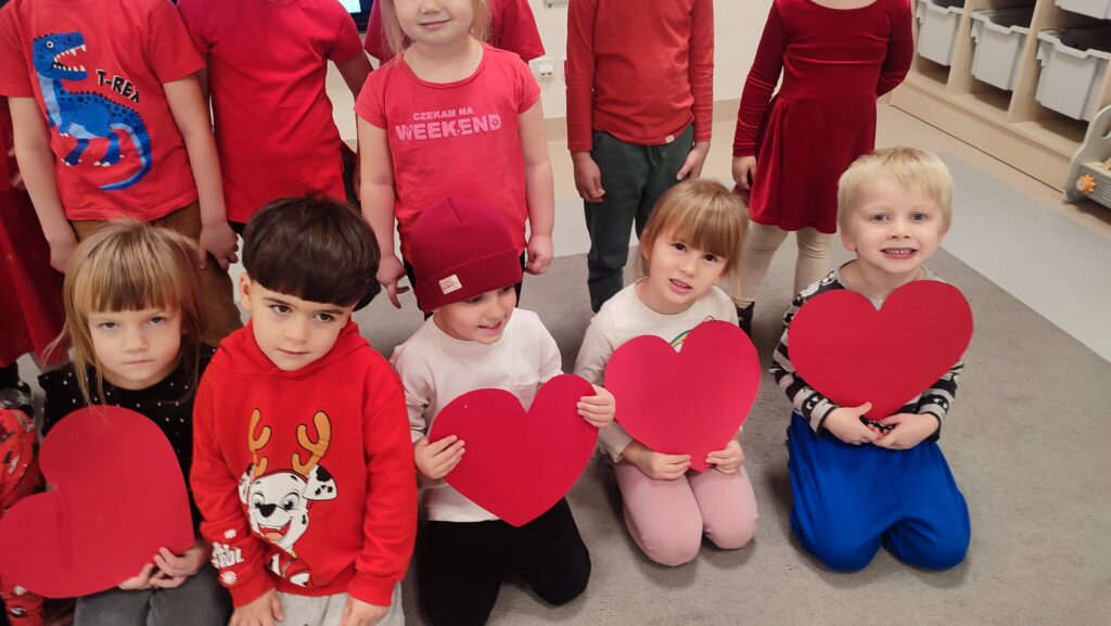 Grupa dzieci ubranych na czerwono pozuje do zdjęcia w rękach trzymają czerwone serca.
