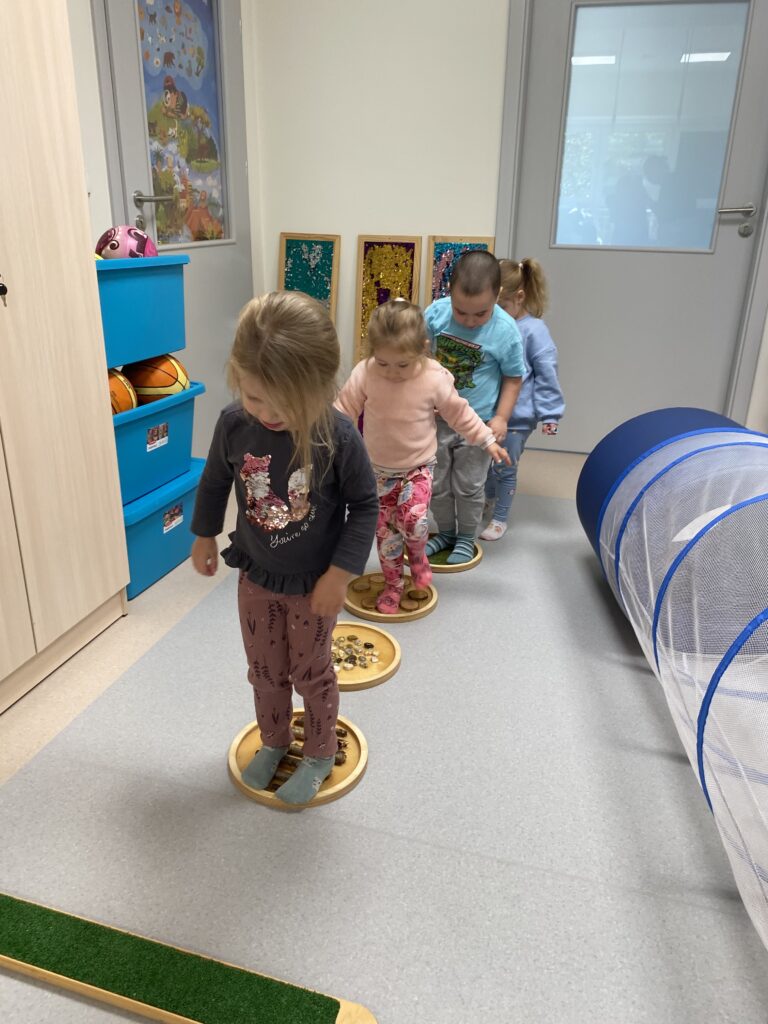Dzieci chodzą po sensorycznych krążkach.