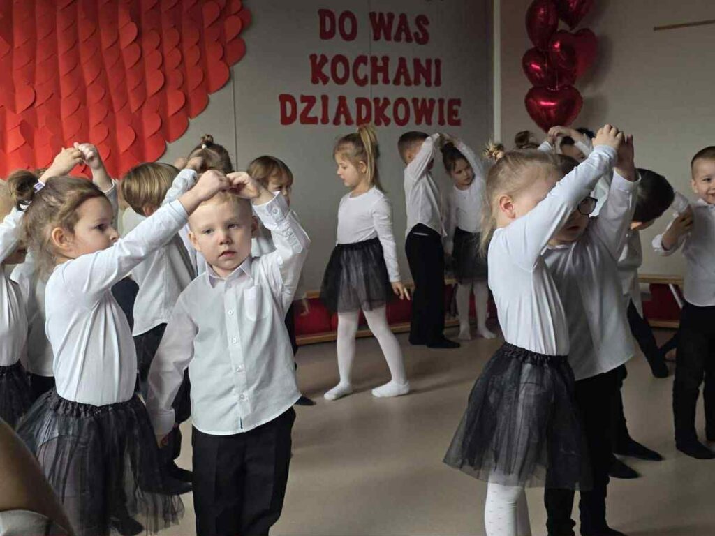 dziewczynki i chłopcy ubrani w biało-czarne stroje tworzą z rąk serce