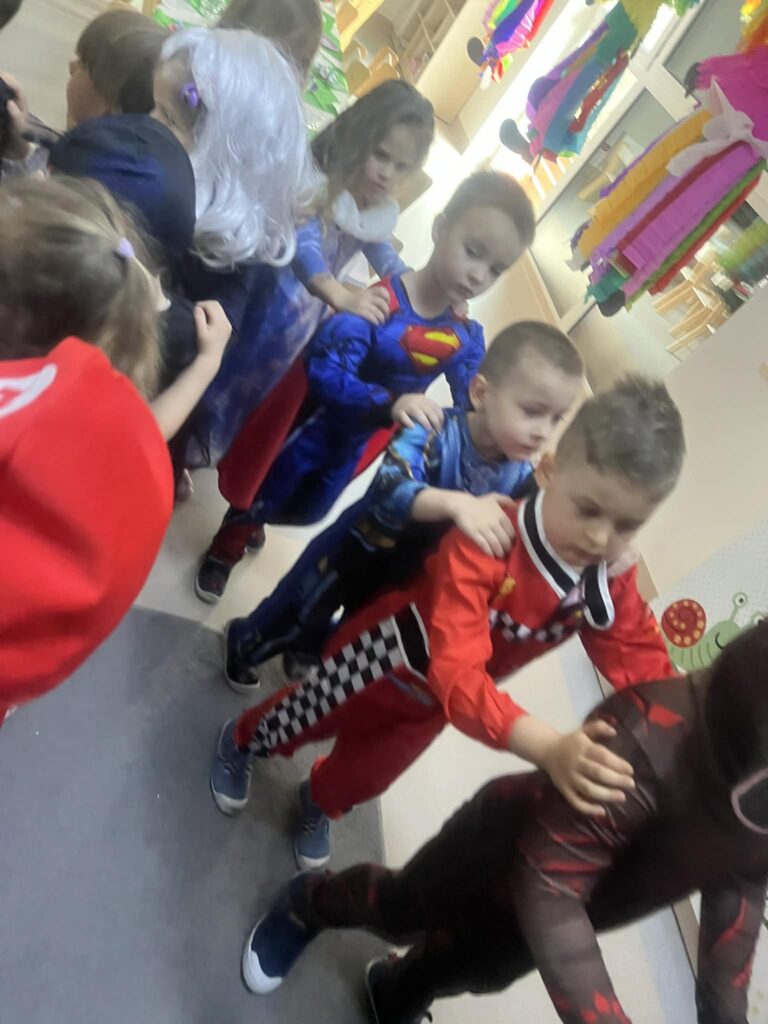 dzieci przebrane w stroje karnawałowe jadą w pociągu trzymając się za ramiona