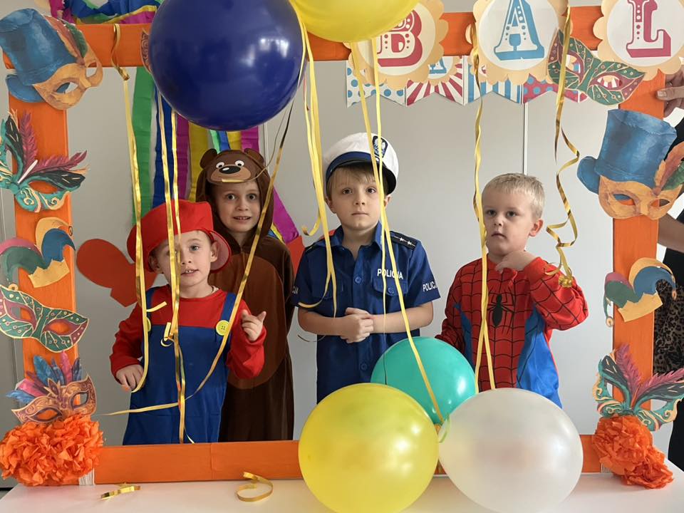 Czworo dzieci stoi w mini foto-budce i pozuje do zdjęcia.