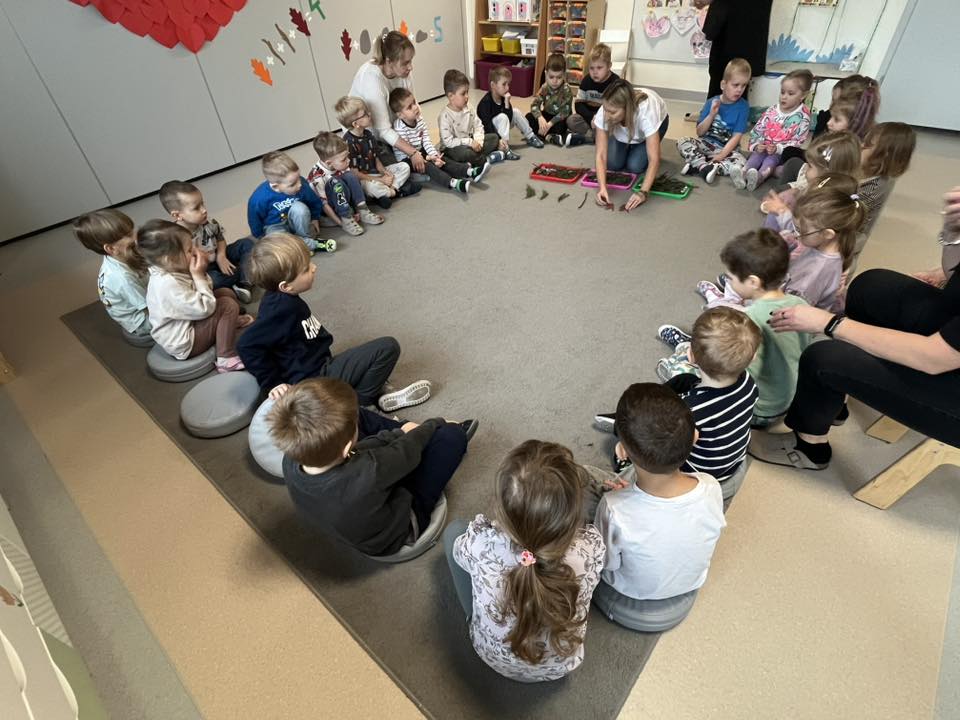 Dzieci siedzą na dywanie w kole. Wybrane podchodzą i układają rytm po nauczycielu.