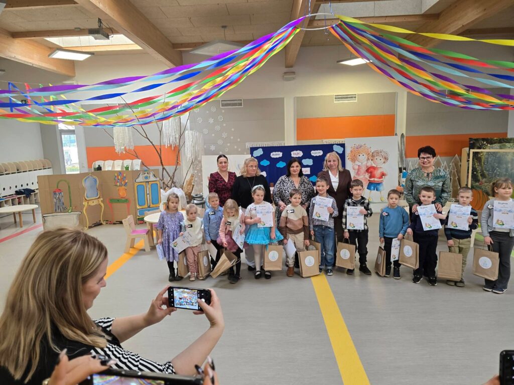 Duża grupa dzieci biorących udział pozuje do wspólnego zdjęcia z otrzymanymi nagrodami.
