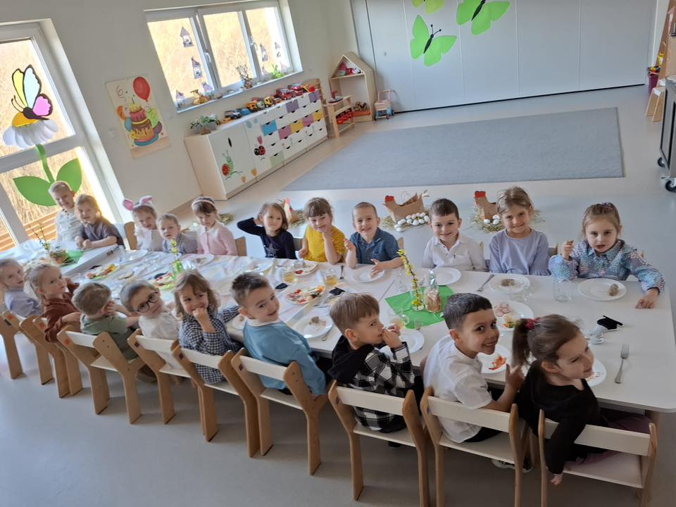 Dzieci siedzą przy wielkanocnym stole