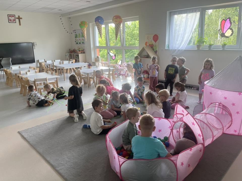 dzieci bawią się na dywanie i w różowym domku w basenie z piłkami 