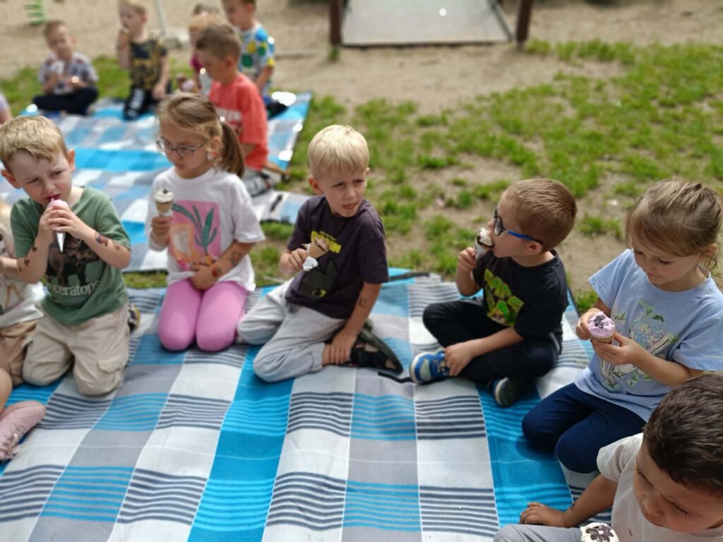 dzieci jedzą lody na kocu na trawie