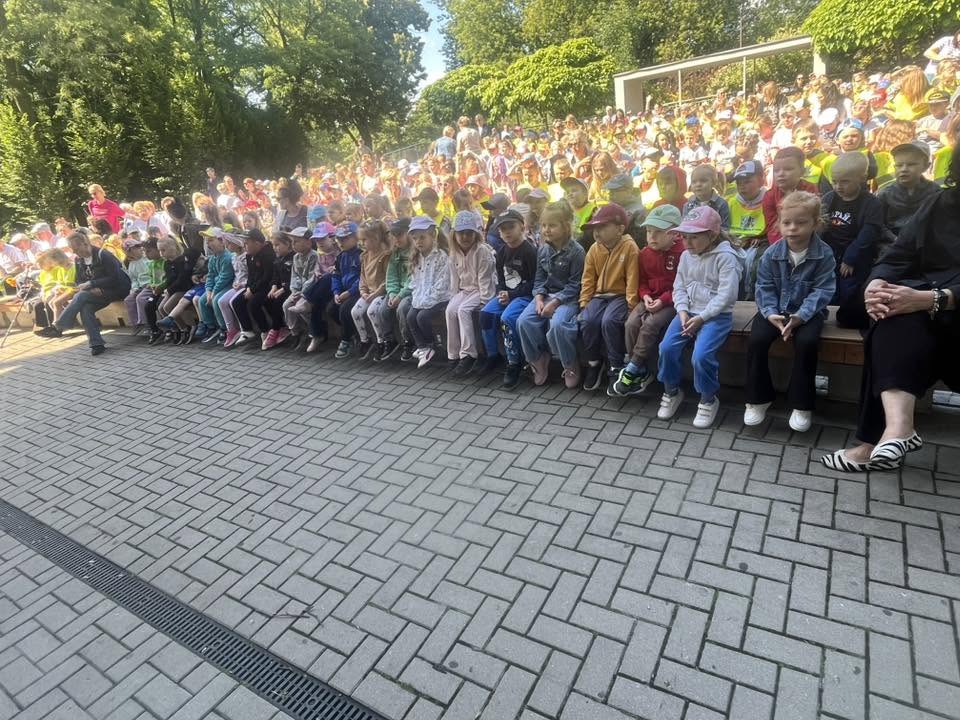 dzieci i panie siedzą na ławkach