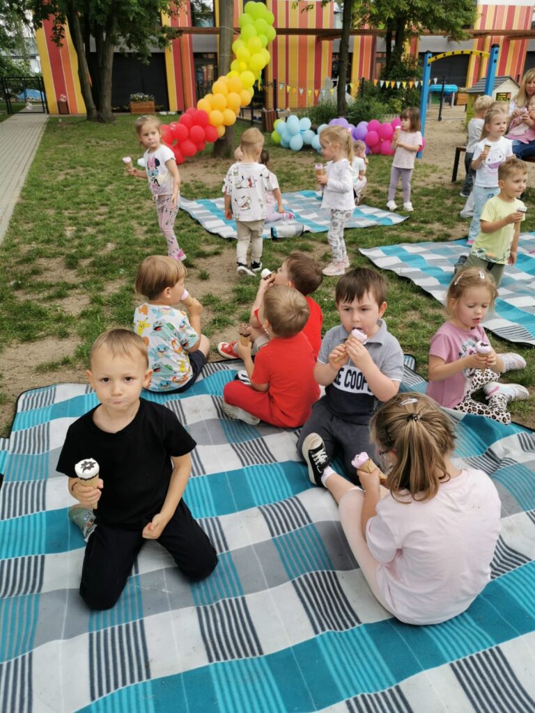 Dzieci siedzą na kocach n a placu zabaw