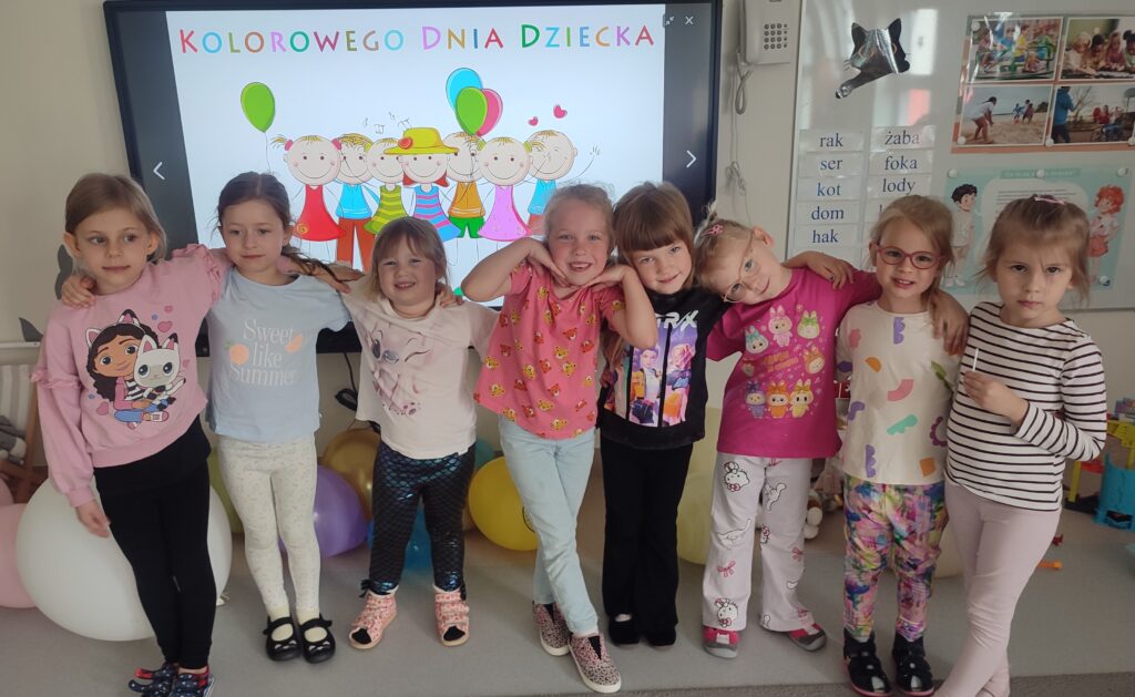 Grupa dziewczynek ubranych w kolorowe stroje pozuje do wspólnego zdjęcia.