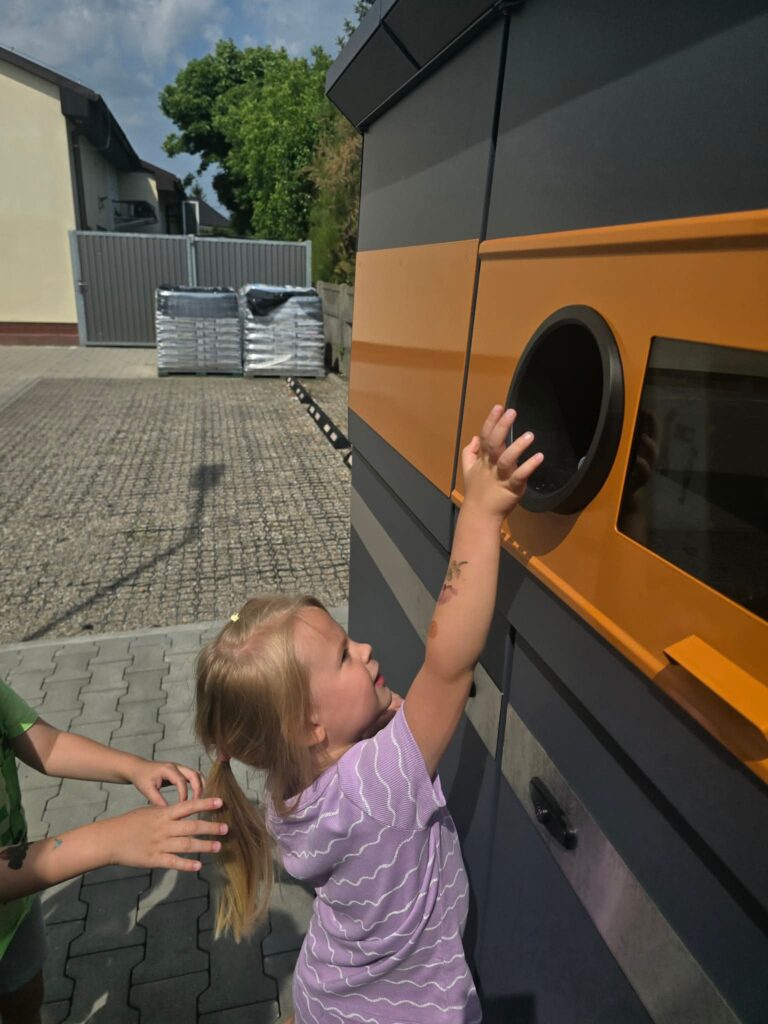 Dziecko stoi przed butelkomatem i wrzuca butelkę do otworu.
