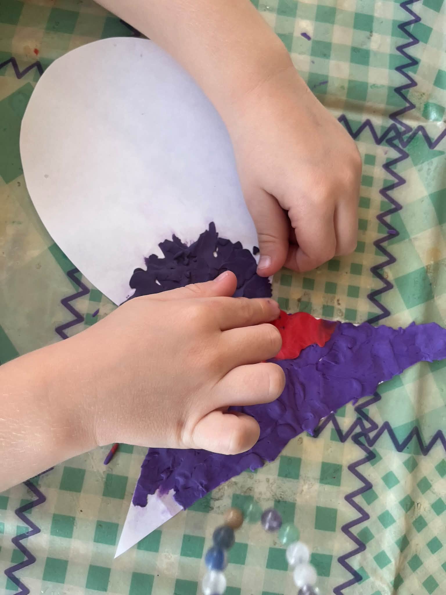 Ręce dziecka, które wyklejają plasteliną rybę