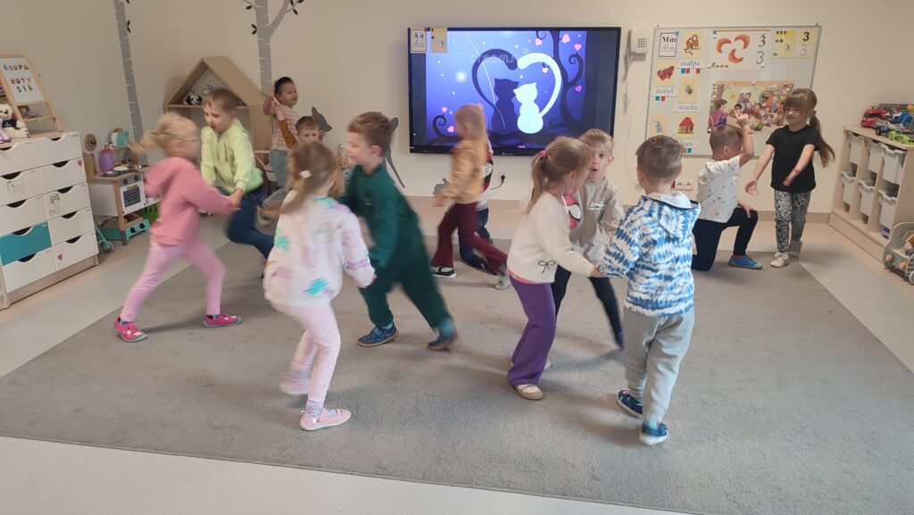 Dziewczynki i chłopcy tańczą w parach do muzyki dziecięcej.