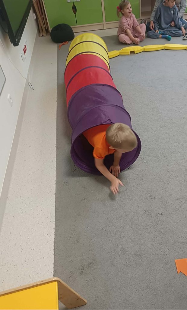 Chłopiec pokonuje tor sensoryczny, przechodzi przez tunel. 